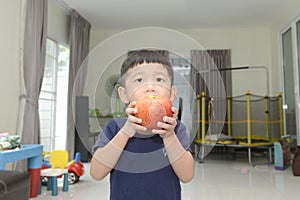 Little Asian boy with a big apple in his hands