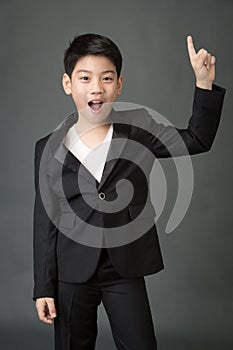 Little asian boy in black suit point up
