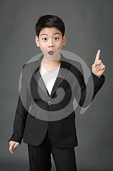 Little asian boy in black suit point up