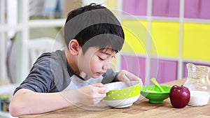 Little asian Boy eating cereal with milk with smile face