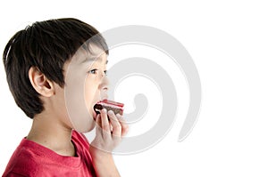 Little asian boy eating long cherry cake isolate on white background