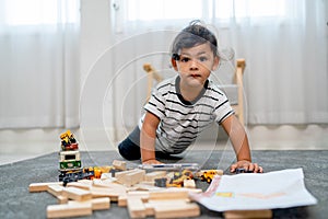 Little Asian boy enjoy to play toy on floor with carpet also look at camera in concept of creative activity for children learning