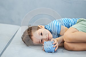 Little asian boy holds a piggy bank in his hands. money saving concept