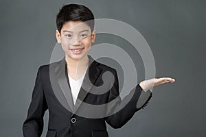 Little asian boy pointing to space at right with palm up