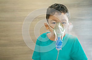 Little asian boy sick child making inhalation with nebulizer steam.