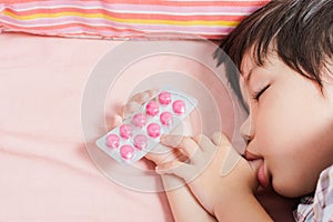 Little Asian Boy Sleep with Medicine panel in hand.