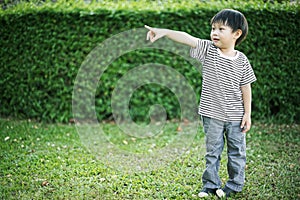 Little asian boy standing and pointing his finger