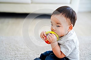 Little Asian boy sucking toy at home