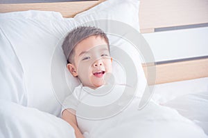Boy waking up on bed and smiling at camera
