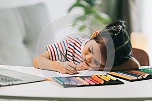 little asian child drawing with color pencils on table at home