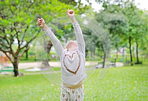 Little Asian child girl Arms up her hands and looking up in the summer garden