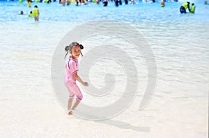 Little Asian child girl enjoys and running into big Swimming pool outdoor on holidays. Rear view children having fun