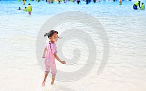 Little Asian child girl enjoys and running into big Swimming pool outdoor on holidays. Rear view children having fun