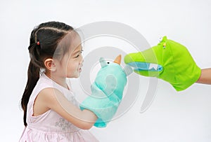 Little Asian child girl hands playing animal puppets with hand of her mother on white background. Educations concept photo