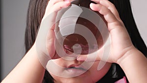 Little Asian child girl holding and look into a magic crystal glass ball in room.