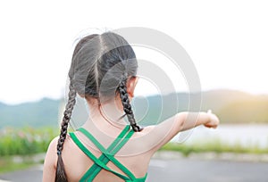 Little Asian child girl pointing up in summer field outdoor. Freedom style outdoor