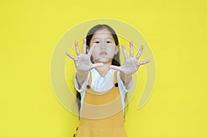 Little asian child girl showing finger number ten isolated on yellow background. Kid counting with fingers for education concept.