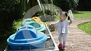 Little Asian child girl throwing empty plastic bottle into the recycle trash in park