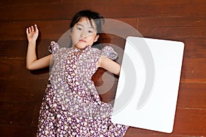 Little Asian child laying down on the wooden background with a b