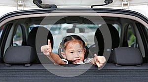 Little asian child looking camera from the hatchback door of the car