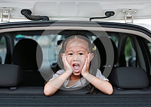 Little asian child looking camera from the hatchback door of the car