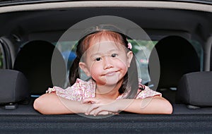 Little asian child looking camera from the window of the car