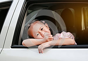 Little asian child looking camera from the window of the car