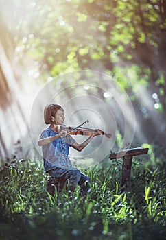 Little Asian child playing violin at outdoors