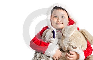 Little Asian fat boy in santa costume hugging rabbit doll on christmas