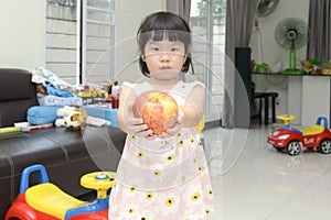 Little Asian girl with a big apple in her hands