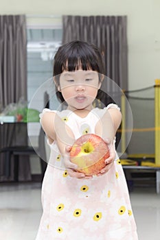 Little Asian girl with a big apple in her hands