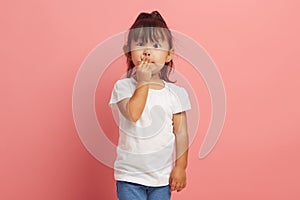 Little Asian girl covers her mouth with her hand with her eyes wide open in shame, said something superfluous and photo