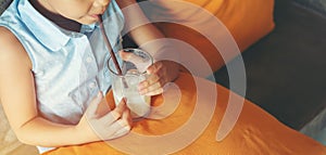 Little asian girl drinking water from glass via straw