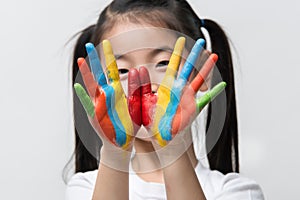 Little Asian girl with hands painted in colorful paints.