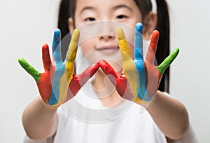 Little Asian girl with hands painted in colorful paints.