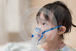 Little asian girl having a medical inhalation treatment with a nebulizer at the hospital
