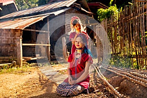 Little Asian girl help to set and decorate hair of her older sister and stay near road in Long Neck Karen Village in Thailand with