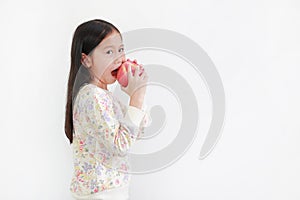 Little asian girl holding and bite red apple over white background. Side view