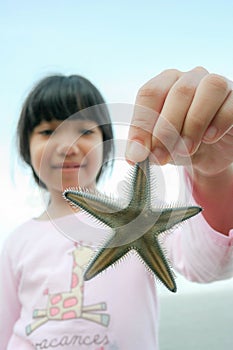Little Asian girl holding starfish