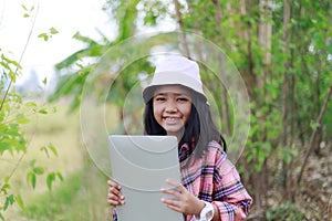 The little Asian girl holding tablet at the tropical farm