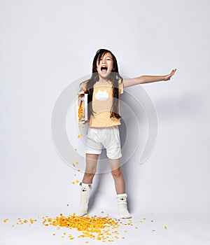 Little asian girl kid poured out her cornflakes breakfast on the floor while yawing and stretching at the morning photo