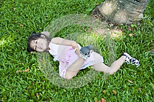 Little asian girl lying on green grass.