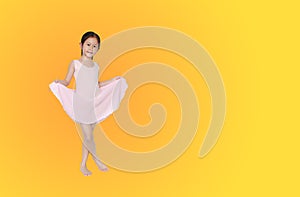 Little asian girl in pink leotard practise her ballet dance isolated on orange-yellow background with copy space. Children is