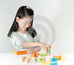 Little Asian girl playing colorful wood blocks