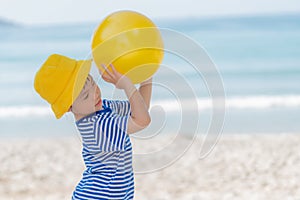 Little asian girl playing yellow ball on the beach in summer. Little girl have enjoy and happy.