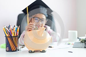 Little Asian girl putting the coin into piggy bank and smile with happiness for money saving to wealthness in the future of