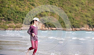 Little Asian girl run play waves on the beach