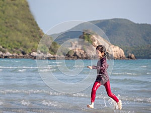 Little Asian girl run play waves on the beach