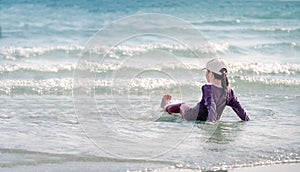 Little Asian girl run play waves on the beach