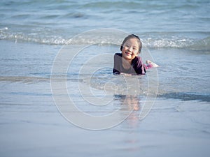 Little Asian girl run play waves on the beach